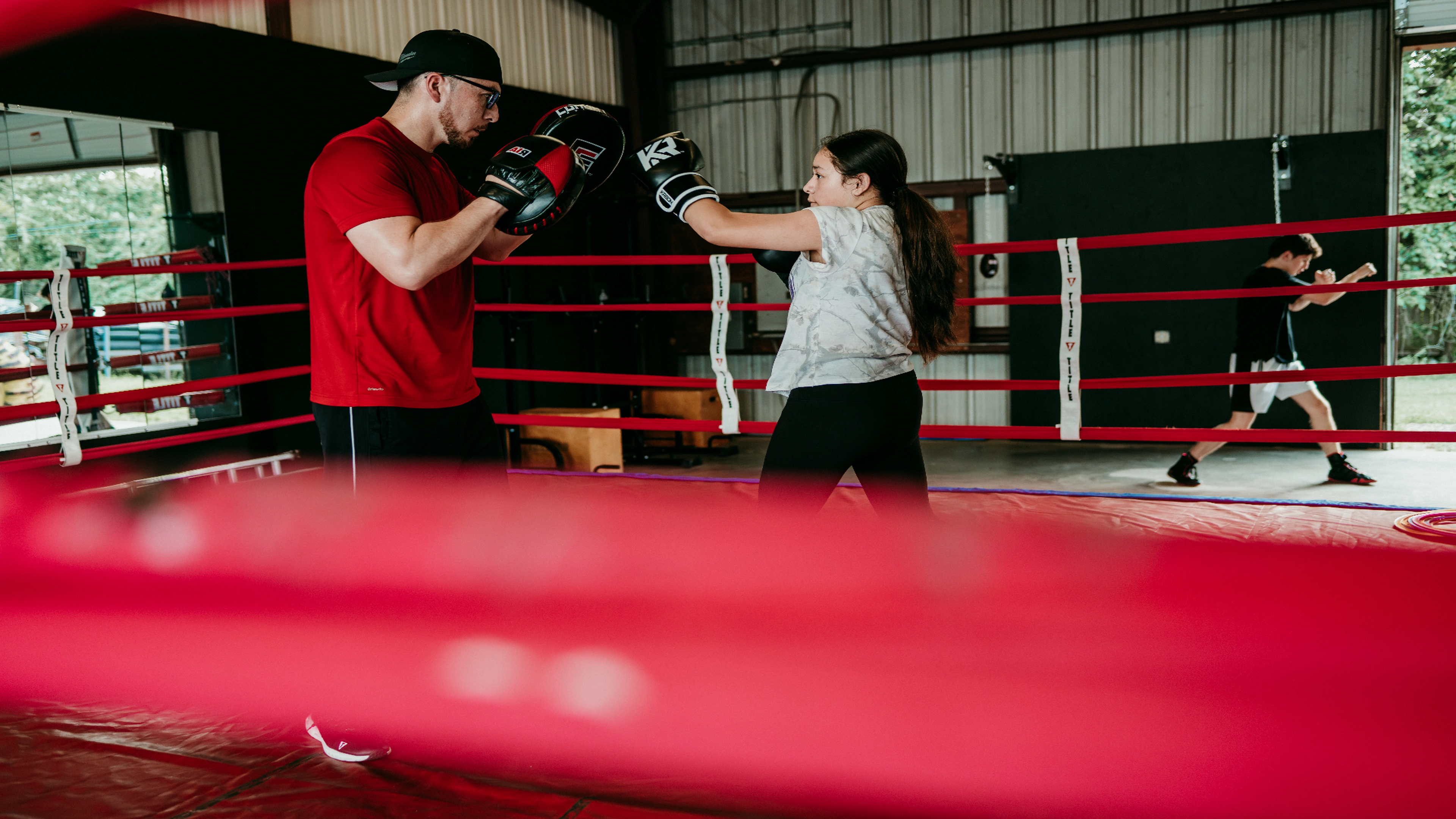 Coach holding mitts for a boxer inside the ring