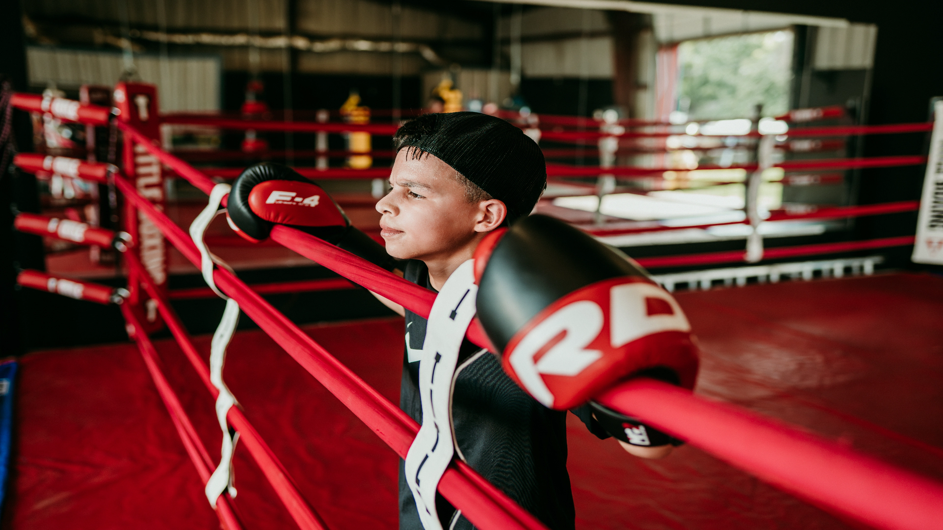 Young boxer resting on the ropes during training